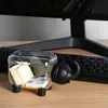 A clear plastic elephant-shaped container filled with sticky notes sits on a wooden desk next to a computer keyboard. Náhľad obrázku produktu
