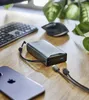 A power bank, smartphone, keyboard, and mouse are arranged on a wooden desk, with a plant in the background. Produktbild-Vorschau