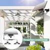 A white pergola structure with solar-powered pendant lights hanging from it. A close-up inset shows the solar panel and two lights. Lush green foliage and blue hydrangeas are in the foreground. Anteprima dell’immagine prodotto
