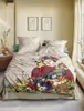 A bedroom scene with a bed dressed in a duvet cover featuring a portrait of Frida Kahlo and floral motifs. Produktbild-Vorschau