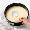 A hand is sifting powdered sugar into a cake batter in a springform pan. Produktbild-Vorschau