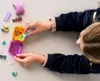 A child's hands are shown interacting with a small, portable toy set, which appears to be a miniature animal-themed business. Náhled obrázku produktu