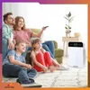 A family is sitting on the floor and couch, watching TV, with an air purifier in the background. Podgląd zdjęcia produktu