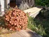 A rusty metal sphere made of flower shapes sits on a wooden surface next to a wooden bench and plants. Anteprima dell’immagine prodotto