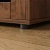 A close-up view of the bottom of a wooden dresser or cabinet, showing one of its feet resting on a wooden floor. Náhľad obrázku produktu