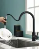 A hand is shown rinsing a dirty plate under a black kitchen faucet with a pull-out spray. Produktbild-Vorschau