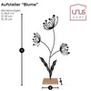 A black metal silhouette of a flower with a wooden base, shown with measurement indicators and text labels. Produktbild-Vorschau