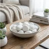 Weiße Kieselsteine in einer dekorativen Schale auf einem Holz-Couchtisch im Innenraum Produktbild-Vorschau