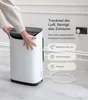 A person's hands are shown adjusting the top of a white and black dehumidifier, which is plugged into a wall socket. Text overlays describe its features. Anteprima dell’immagine prodotto