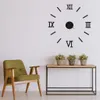 A wall clock with Roman numerals is displayed on a white wall above a wooden console table with three potted plants. Náhľad obrázku produktu