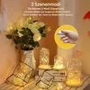 A decorative arrangement of LED string lights in glass containers and geometric frames, alongside a bouquet of white flowers. Produktbild-Vorschau