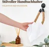 A hand is holding a white towel, demonstrating a rope-style towel holder mounted on a wall. A diffuser with reeds is visible on a shelf below. Anteprima dell’immagine prodotto