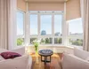 A bright, modern living room with large windows offering a city view. Anteprima dell’immagine prodotto