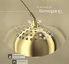 A close-up of a gold-colored arc lamp with a perforated shade, showing its adjustable movement and design details. Náhled obrázku produktu