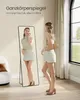 A woman is checking her outfit in a full-length mirror in a well-lit room. Produktbild-Vorschau