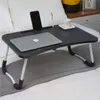A black folding lap desk with a laptop, phone, and cup on it, placed on a bed. Anteprima dell’immagine prodotto