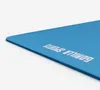 A close-up, angled view of a blue yoga mat with the brand name printed on it. Produktbild-Vorschau