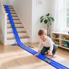 A young boy plays with a toy car race track set on the floor next to a staircase. Produktbild-Vorschau