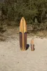 Two wooden surfboards of different sizes stand on a sandy beach with trees in the background. Produktbild-Vorschau