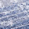 A close-up, textured view of a rug with an abstract pattern in shades of blue, gray, and white. Produktbild-Vorschau