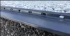 A close-up view of a gray aluminum drainage profile with small white and gray pebbles embedded in it. Produktbild-Vorschau