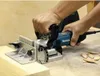A person is using a Makita PJ 7000J Nutfräse Flachdübelfräse to join two pieces of wood. Several wooden dowels are scattered on the surface next to the tool. Podgląd zdjęcia produktu
