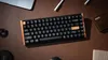 A keyboard is placed on a brown leather desk with other office supplies. Produktbild-Vorschau