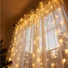 A curtain of warm white fairy lights hanging over a sheer white curtain in a window. Náhľad obrázku produktu