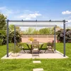 A patio set with a pergola and dining table in a backyard garden. Voir les images du produit