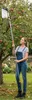 A woman is using an apple picker in an orchard. Produktbild-Vorschau