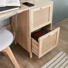 A close-up view of a wooden desk with rattan accents, showing an open drawer with books inside, and a clear chair next to it. Anteprima dell’immagine prodotto