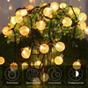 A string of solar-powered LED lights with spherical bulbs, displayed around a potted plant. Voir les images du produit