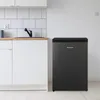 A small black refrigerator is placed next to white kitchen cabinets and a countertop with a sink. Produktbild-Vorschau