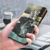 A hand holding a wallet-style phone case with a cat and tiger reflection design. A coffee cup is visible in the background. Produktbild-Vorschau