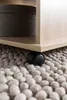 A close-up view of a wooden table's caster wheel resting on a textured rug. Produktbild-Vorschau