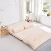 A beige floor sofa is laid out flat in a bright room with large windows. Voir les images du produit