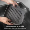 A person is washing a gray silicone baking pan in a kitchen sink. Náhľad obrázku produktu