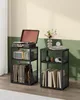 Two black metal shelf units are shown side-by-side in a room with a pale yellow and green wall. The left unit holds a record player on top, a speaker and CDs on the middle shelf, and records on the bottom shelf. The right unit holds books and headphones. Náhled obrázku produktu