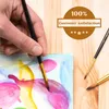 A hand is painting on a canvas with watercolor brushes and paints. Podgląd zdjęcia produktu