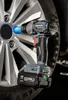 A cordless impact wrench is shown attached to a car wheel, with a battery pack on its base. Podgląd zdjęcia produktu