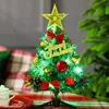 A small, decorated Christmas tree sits on a table with a mug and candy canes nearby. Náhled obrázku produktu