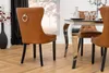 A dining chair with a brown faux leather finish and a silver ring on the back, part of a dining set. Produktbild-Vorschau