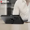 A person wearing a white shirt is in the background, and a black phone case with a ring holder is in the foreground, placed on a table. Produktbild-Vorschau
