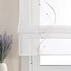 A close-up view of a white sheer roman blind with decorative beaded strands and a lavender plant in a vase. Produktbild-Vorschau