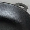 A close-up view of the textured surface and handle of a black cast iron pan. Voir les images du produit
