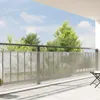 A balcony with a railing and a protective screen, with trees and sky in the background. Podgląd zdjęcia produktu