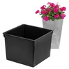 A black square planter insert is shown in the foreground, with a grey planter containing pink flowers in the background. Náhled obrázku produktu