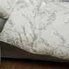 A close-up view of a white duvet cover with a delicate green floral pattern. Produktbild-Vorschau