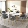 A dining room set with a white marble table and six gray upholstered chairs with gold legs. Produktbild-Vorschau