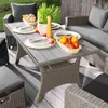 An outdoor patio setting with a rattan-style lounge furniture set including a table, sofa, chairs, and ottomans. Náhled obrázku produktu